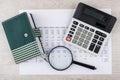 Electronic calculator, magnifying glass and notepad with pen on