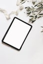 Electronic device mock-up. Closeup of tablet with empty screen. Olive tree branches and silk ribbon isolated on white Royalty Free Stock Photo