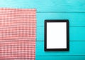 Electronic device with place for text and plaid tablecloth on blue wooden background. Top view and copy space. Royalty Free Stock Photo