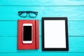 Electronic devices with places for text. Notebook and glasses. Blue wooden background and top view