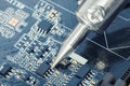 Electronic manufacturing and repair concept - close up studio shot of soldering iron in a process of fixing microcircuit