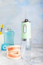 Electronic oral irrigator, toothbrush, paste, dental floss and mouthwash on background.