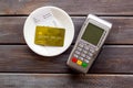 Electronic payments in restaurant. Bank card near aquiring terminal and bill on dark wooden background top view Royalty Free Stock Photo