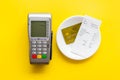 Electronic payments in restaurant. Bank card near aquiring terminal and bill on yellow background top view Royalty Free Stock Photo