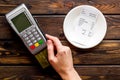 Electronic payments in restaurant. Hand bring bank card to terminal near bill on dark wooden background top view Royalty Free Stock Photo