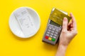 Electronic payments in restaurant. Hand bring bank card to terminal near bill on yellow background top view Royalty Free Stock Photo