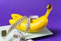 On the electronic scale are two bananas and a measuring tape on a purple background Royalty Free Stock Photo