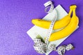 On the electronic scale are two bananas and a measuring tape on a purple background Royalty Free Stock Photo