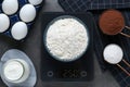 Electronic scales with flour and different products on black table, flat lay Royalty Free Stock Photo