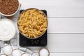 Electronic scales with uncooked pasta and different products on white wooden table, flat lay. Space for text Royalty Free Stock Photo