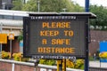 An electronic signboard outside a train station stating please keep a safe distance during the coronavirus pandemic