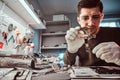 Electronic technician mending a broken tablet carefully examines the chip of the tablet using a magnifying glass