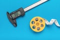 An electronic vernier caliper and a coil with a measuring tape on a blue background Royalty Free Stock Photo