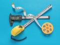 An electronic vernier caliper, a reel with measuring tape and a tape measure on a blue background Royalty Free Stock Photo