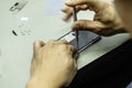 An electronics technician disassembling a smart mobile phone on the table in his workshop