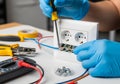 Electronics workbench featuring a double power outlet being wired. Hands in blue protective gloves Royalty Free Stock Photo