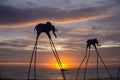 Elefanten auf Stelzen als Touristenattraktion am Sunset Sanato Beach Club bei Sonnenuntergang mit Fischerboot im Hintergrund in