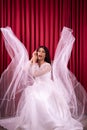 Elegance Asian woman wearing a wedding dress with flying fabric around her in front of the red curtain Royalty Free Stock Photo