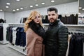 Elegance blonde girl in fur coat and stylish turkish man at the store of fur coats and leather jackets