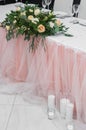 Elegance in Bloom: Wedding Table adorned with Pink Tablecloth and White Tulle, Centerpiece Featuring a Variety of Beautiful Royalty Free Stock Photo