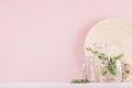 Elegance home eco decor - aromatic bouquet of fresh rosemary in glass vase and wooden beige plate, sticks on pink white table.