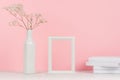 Elegance home interior of small dry flowers in vase, white books and blank wood photo frame on light pink background. Royalty Free Stock Photo