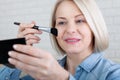 Elegance in Reflection. Captivating shot of a woman skillfully applying makeup before a vanity mirror, creating a timeless beauty