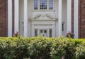 Elegance - Rosebush hedge that needs trimmed in full sun in front of shadowed blurred ornate entrance to upscale brick and stucco