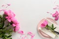 Spring table setting with pink peony flowers on a white table. View from above.