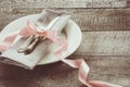 Elegance table set with pink ribbon, white plate on wooden board. Rustic and vintage style. Romantic dinner. Royalty Free Stock Photo