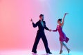 Elegance and tenderness. Young man and woman, ballroom dancers in motion, dancing, performing against gradient pink blue Royalty Free Stock Photo