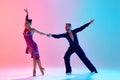 Elegance and tenderness. Young man and woman, ballroom dancers in motion, dancing, performing against gradient pink blue Royalty Free Stock Photo