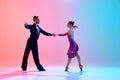 Elegance and tenderness. Young man and woman, ballroom dancers in motion, dancing, performing against gradient pink blue Royalty Free Stock Photo