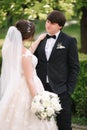 Elegand bride in beautiful white wedding dress with handsome groom in the park. Green background