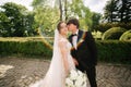 Elegand bride in beautiful white wedding dress with handsome groom in the park. Green background