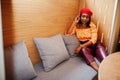 Elegant afro american woman in red french beret, big gold neck chain polka dot blouse and leather pants pose indoor Royalty Free Stock Photo