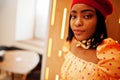 Elegant afro american woman in red french beret, big gold neck chain polka dot blouse pose indoor Royalty Free Stock Photo