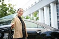 Elegant aged asian businesswoman getting out of the car with happy facial expression