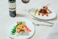 elegant appetizing veal with cherry sauce and turkey with Migdal. in white plates with greens, red wine and table setting Royalty Free Stock Photo