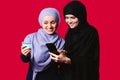 Elegant arab women holding mobile phone and banking card. Businesswomen with stylish hijab paying with credit card while