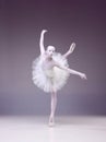 Elegant, artistic young woman, professional ballerina in tutu making creative performance over studio background.