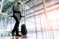 Elegant asian businessman checking email on mobile phone while walking with suitcase inside airport