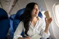 An elegant Asian businesswoman is sipping coffee while looking at the view outside the plane window Royalty Free Stock Photo