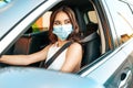 Elegant asian ethnicity woman in a medical face mask driving car.