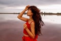 Elegant Asian Woman In Red Dress Walking By A Salt Fantastic Lake At Sunset In Wind.