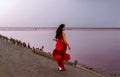 Elegant Woman In Red Silky Dress Walking By A Salt fantastic Lake At Sunset.