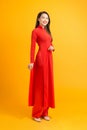 Elegant Asian woman standing over yellow background while wearing Vietnam tradion Ao dai custom Royalty Free Stock Photo