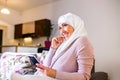 Elegant attractive female muslim using mobile smartphone searching online information when she sitting on sofa couch relaxing.