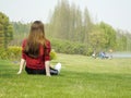 The elegant back of a lady sitting on a scenic lawn