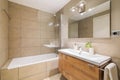 This elegant bathroom features a modern design with beige tiles, a spacious shower, sleek sink and mirror, and luxurious